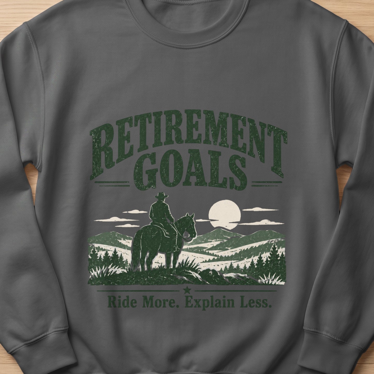 Sweatshirt with "Retirement Goals Ride More. Explain Less." text and a cowboy on horseback.