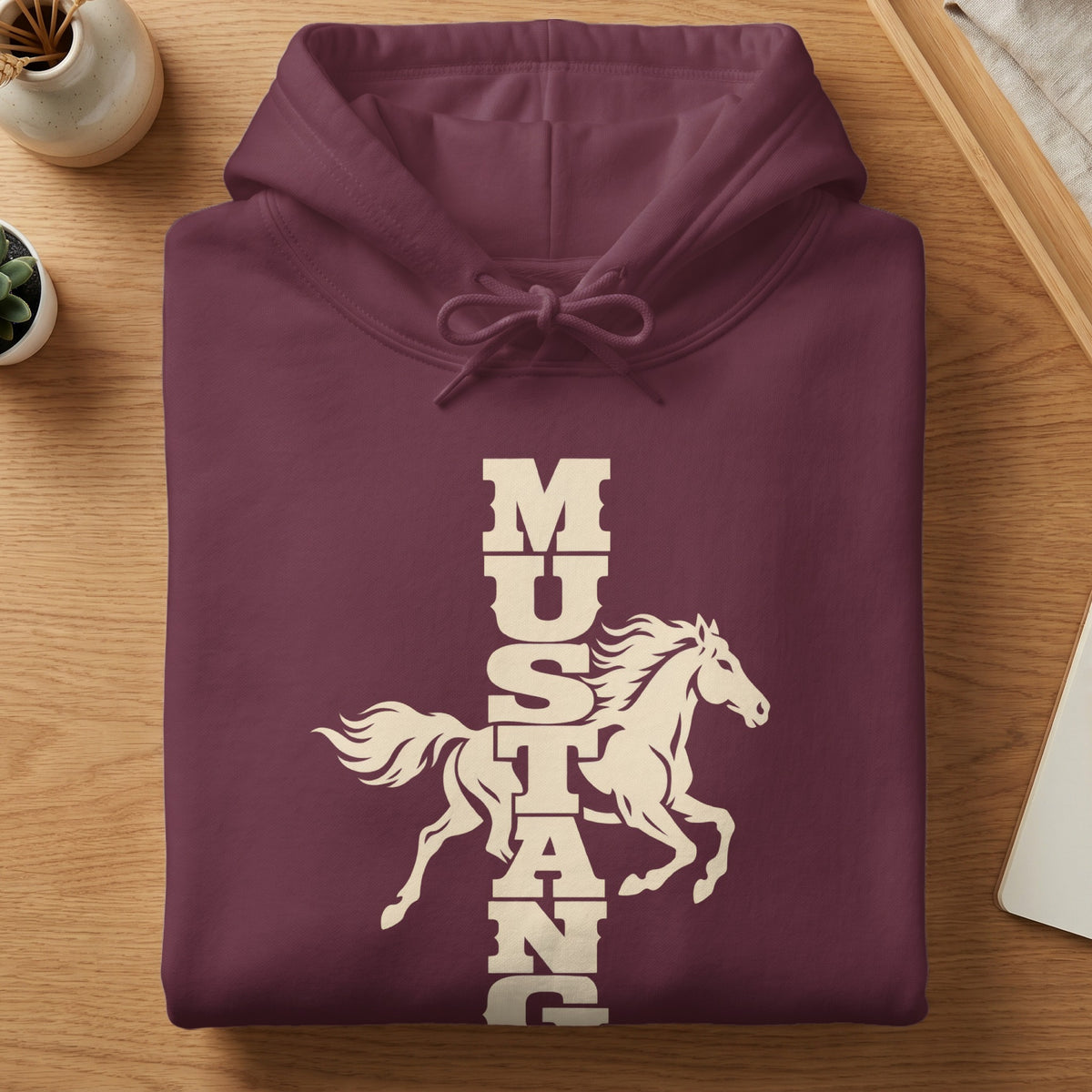 A folded maroon hoodie with a cream graphic of a running horse and vertical Mustang text.