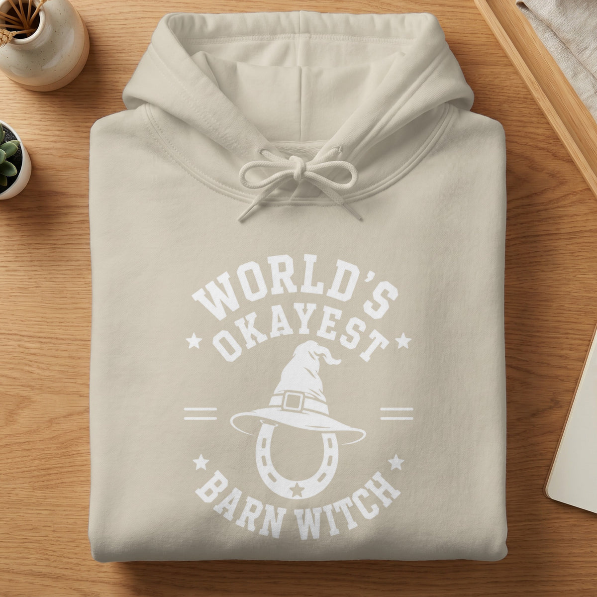 Tan hoodie with white text "World's Okayest Barn Witch" and graphic.