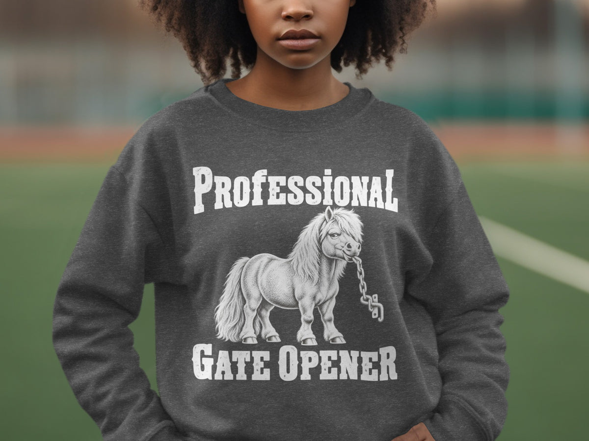 A person wearing a dark grey crewneck sweatshirt featuring a graphic of a pony biting a chain, with the text Professional Gate Opener.