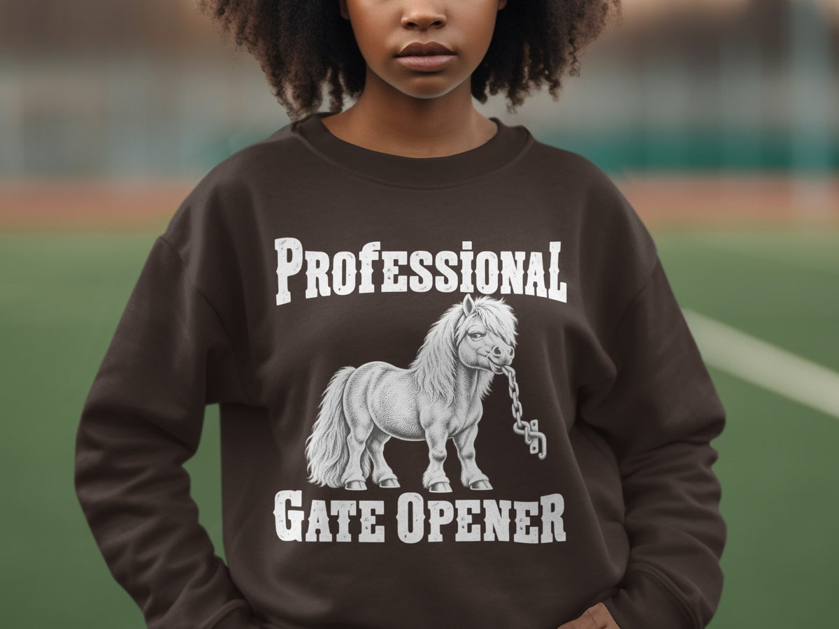 A person wears a brown crewneck sweatshirt featuring a graphic of a pony biting a chain with text reading Professional Gate Opener.