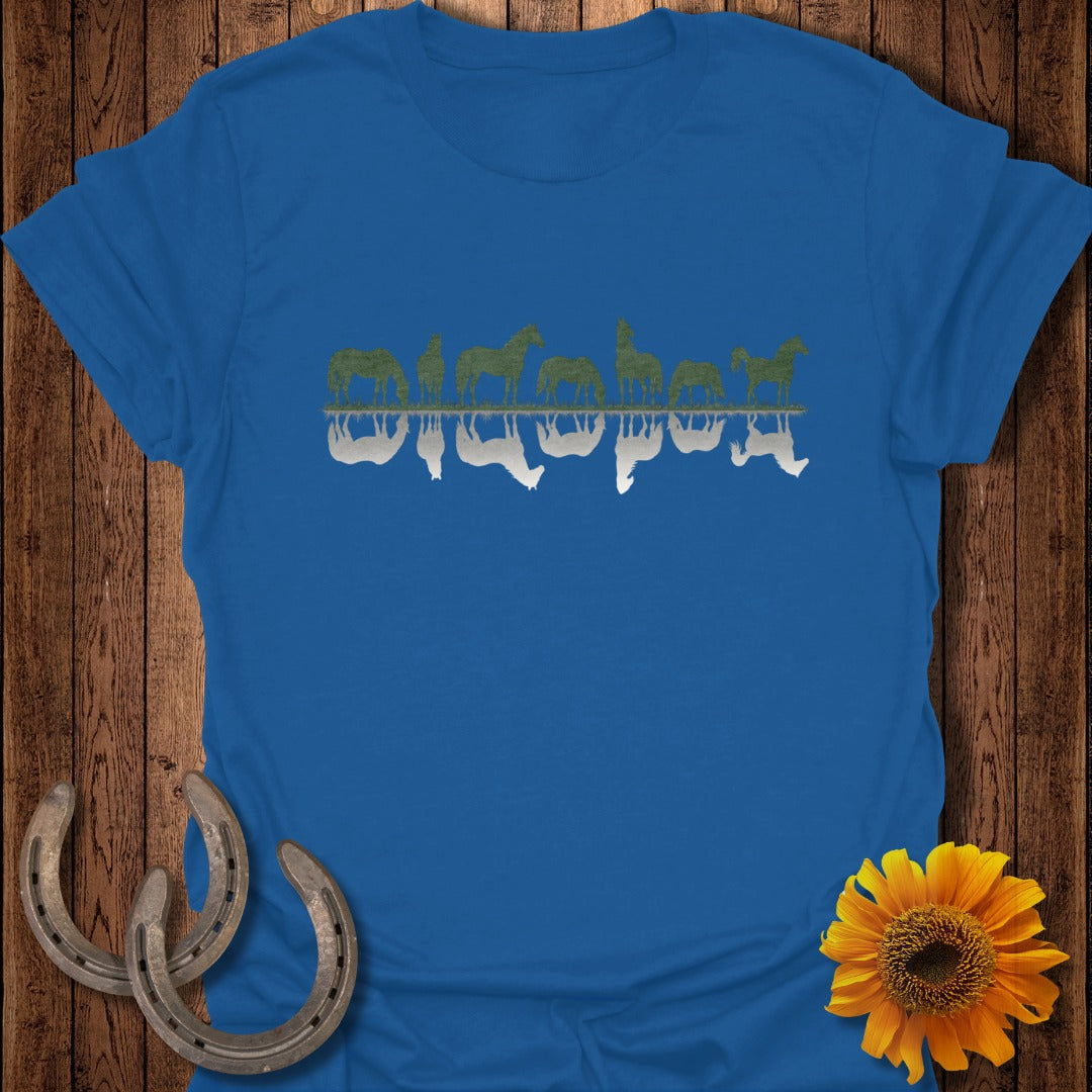 Blue t-shirt with mirrored horse silhouettes on a wooden background.