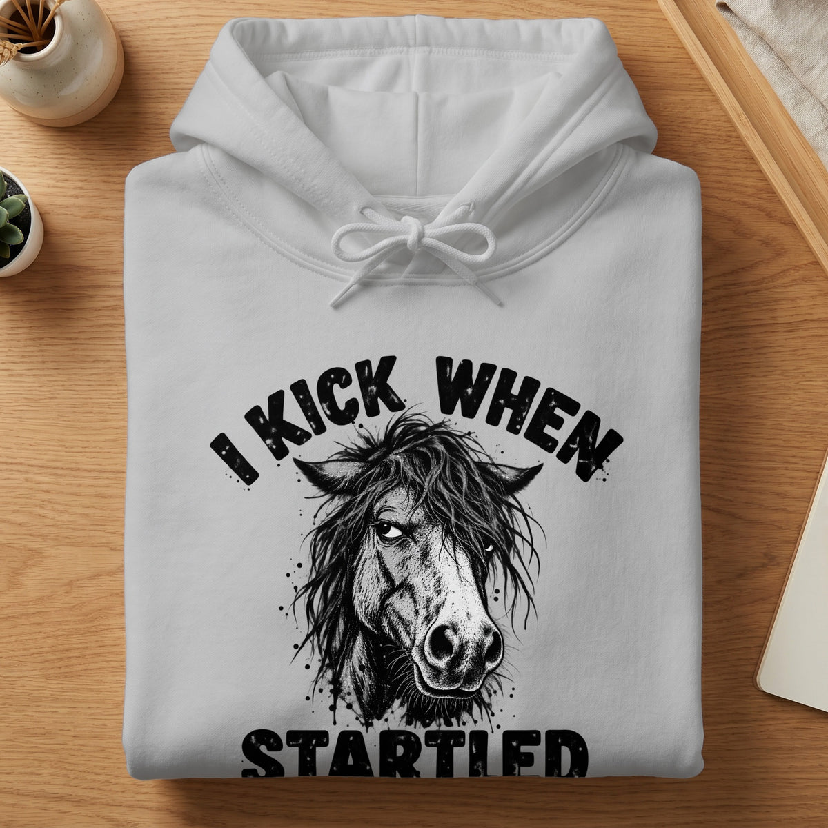 White hoodie with "I kick when startled" text and a horse graphic.