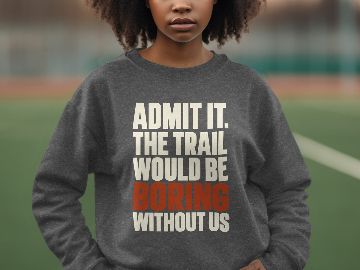 A person wearing a dark gray crewneck sweatshirt with the white and red text, Admit it. The trail would be boring without us.