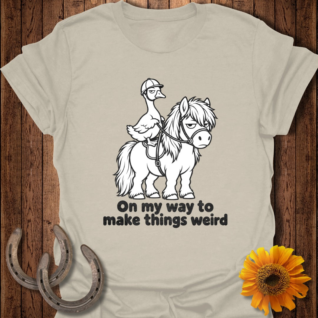 A tan t-shirt features a graphic of a duck wearing a helmet riding a pony, with the text "On my way to make things weird".