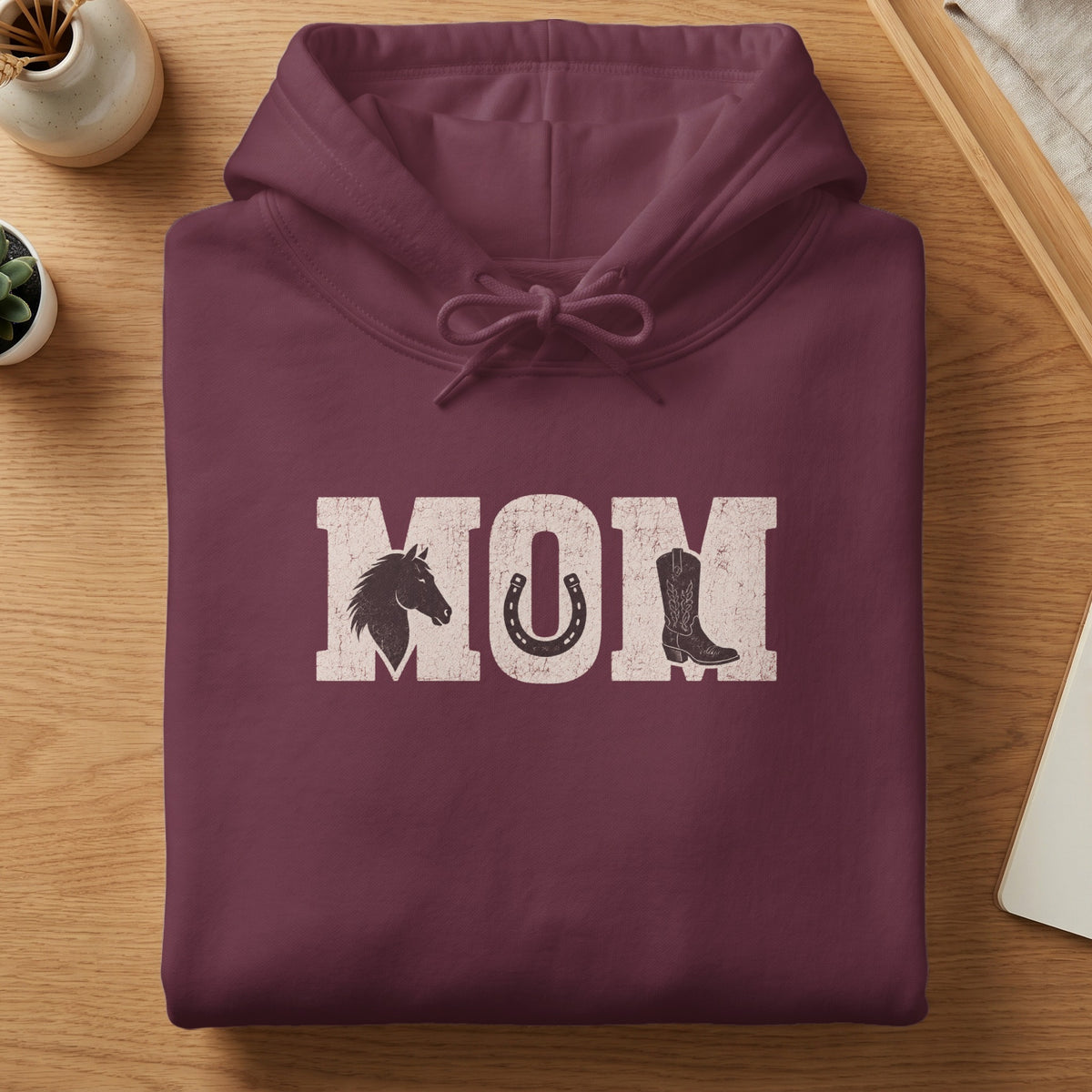 Maroon hoodie with distressed "MOM" text featuring horse head, horseshoe, and cowboy boot graphics.