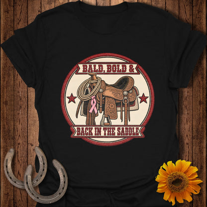Black t-shirt with saddle, rope, pink ribbon, and text: BALD, BOLD & BACK IN THE SADDLE.