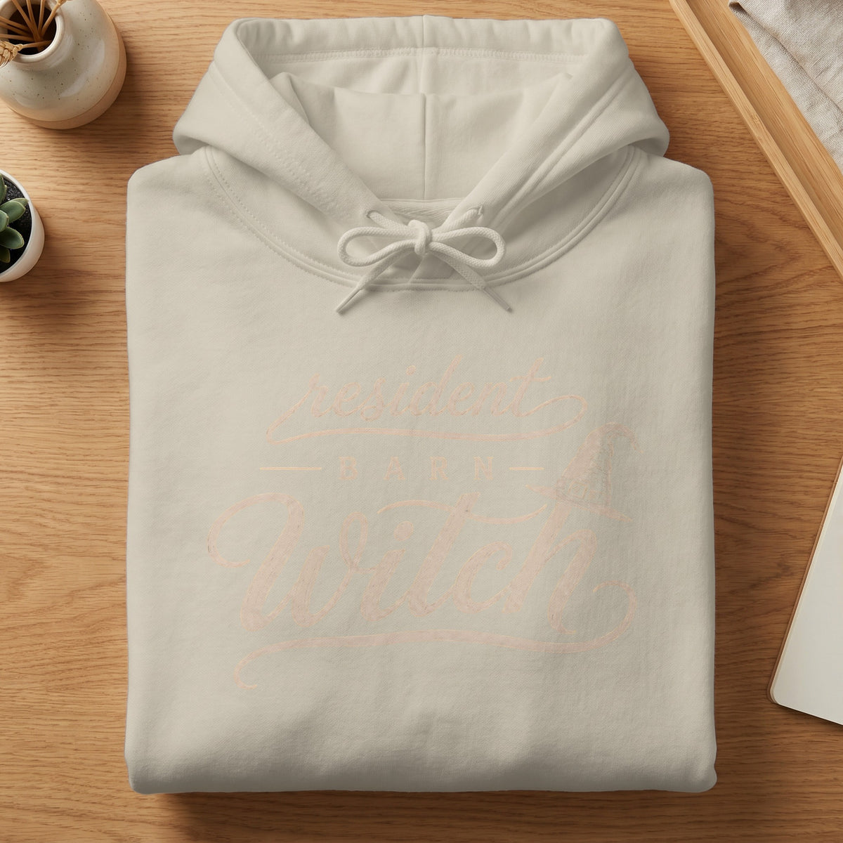 Light cream hoodie with "resident barn witch" text and witch hat graphic.
