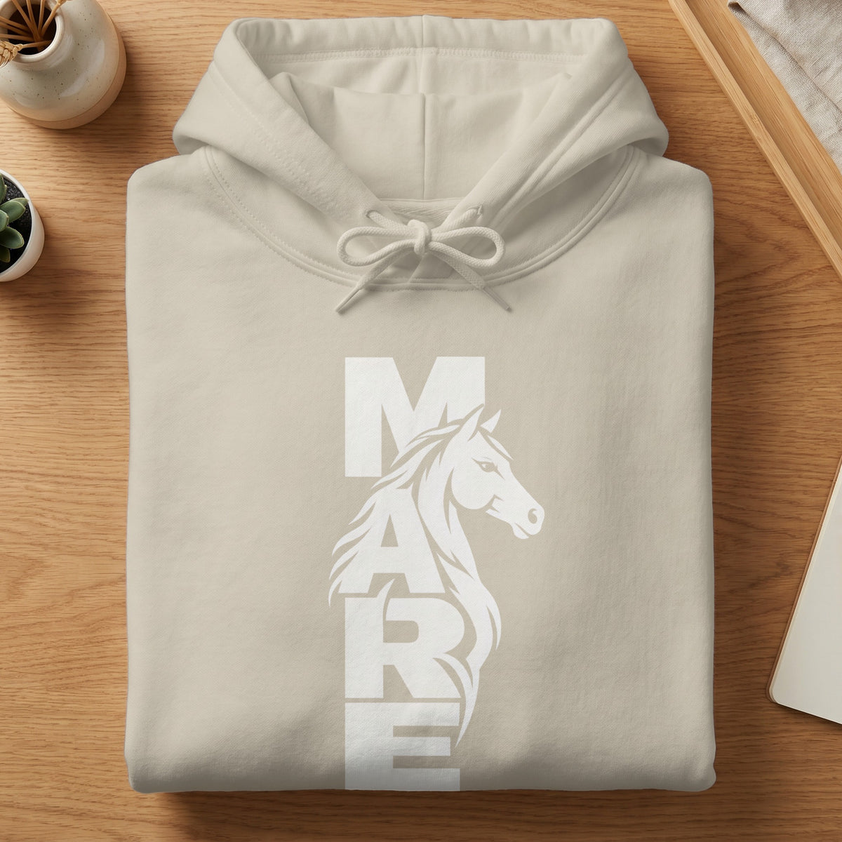 A folded cream-colored hooded sweatshirt featuring a white graphic of a horse head and the text MARE.