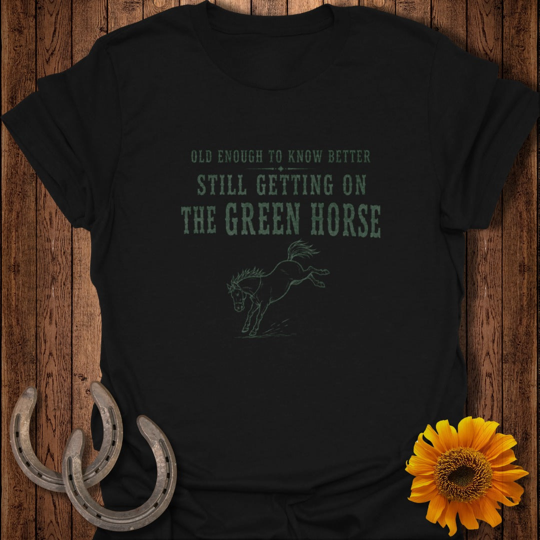 Black t-shirt with green text: "OLD ENOUGH TO KNOW BETTER STILL GETTING ON THE GREEN HORSE" and horse graphic.