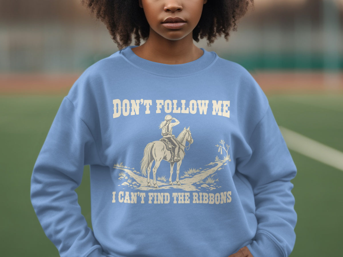 A person wears a light blue crewneck sweatshirt featuring a graphic of a horse and rider.