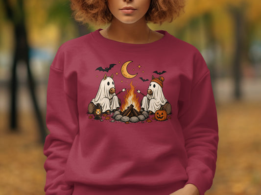 Two horses in ghost costumes roast marshmallows by a campfire under a crescent moon.