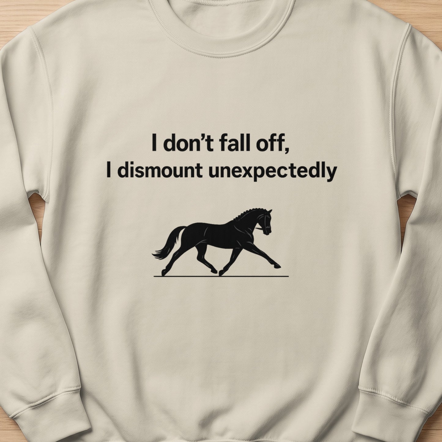 Light cream sweatshirt with black text and horse graphic: "I don't fall off, I dismount unexpectedly."