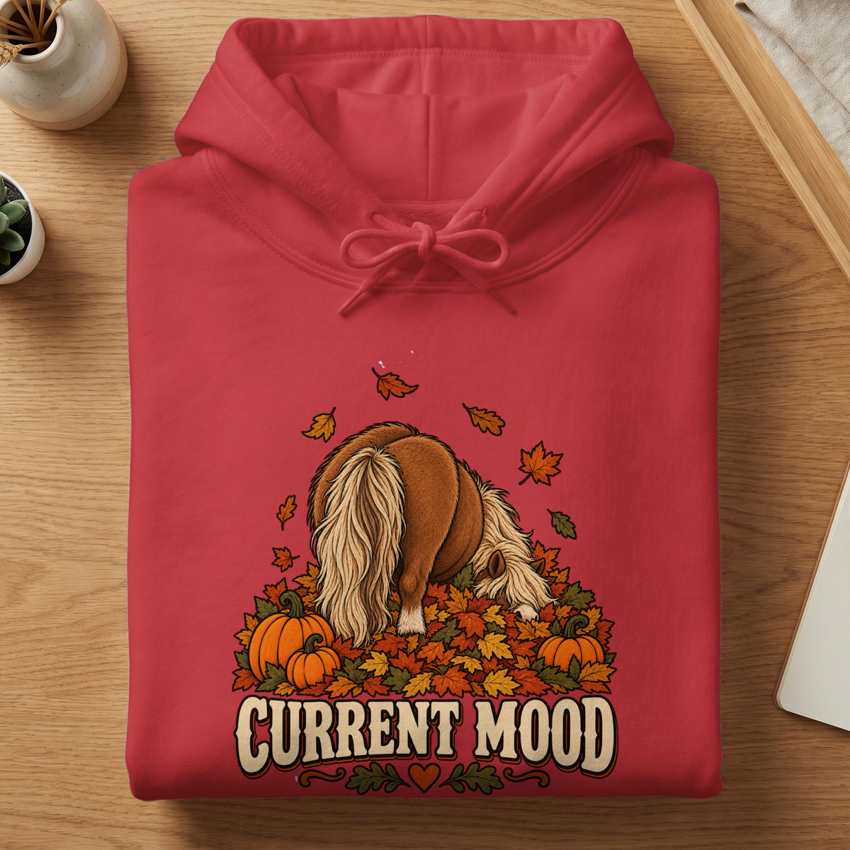 Red hoodie with a pony head buried in autumn leaves and pumpkins, text "Current Mood".