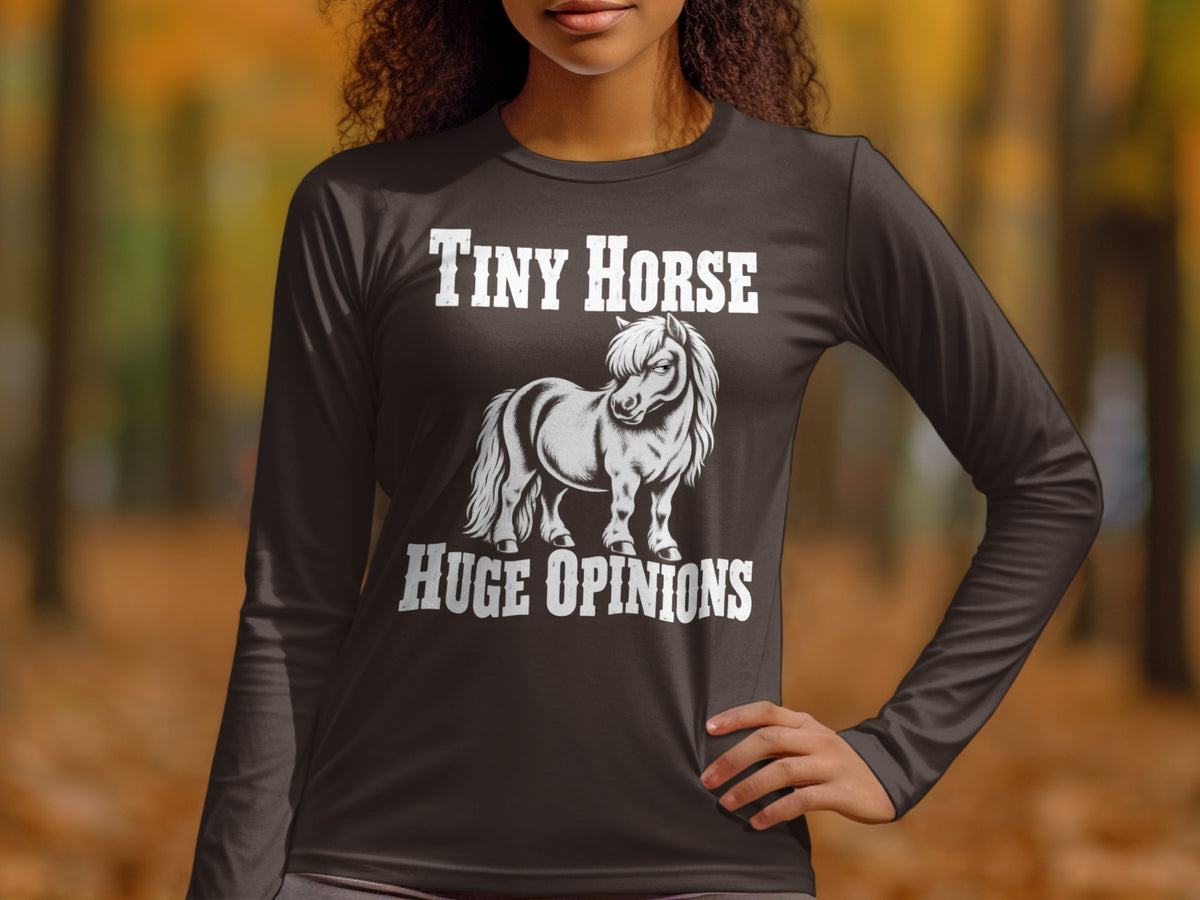 A person wearing a dark grey long-sleeve shirt with a graphic of a small pony and the text Tiny Horse Huge Opinions.