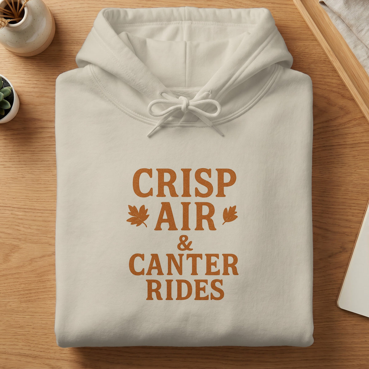 Cream hoodie with "Crisp Air & Canter Rides" text and autumn leaf graphics.