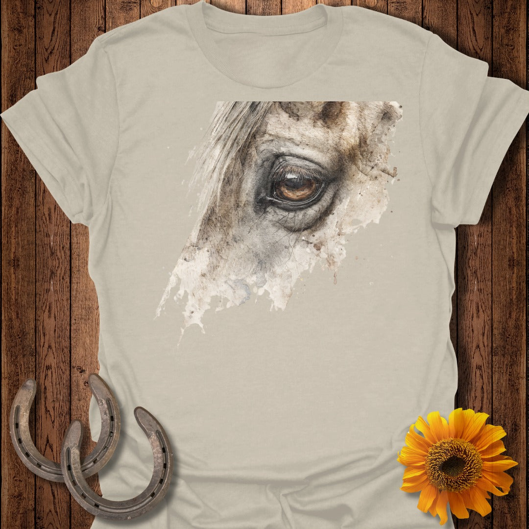 Watercolor close-up of a horse's eye on a tan t-shirt with horseshoes and sunflower.