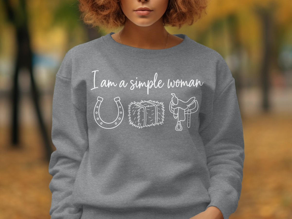 Grey sweatshirt with white text "I am a simple woman" and icons of horseshoe, hay bale, and saddle.