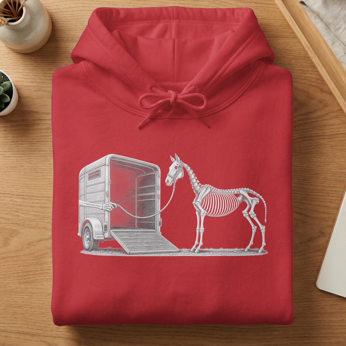 Red hoodie with a line drawing of a horse skeleton being loaded into a trailer.