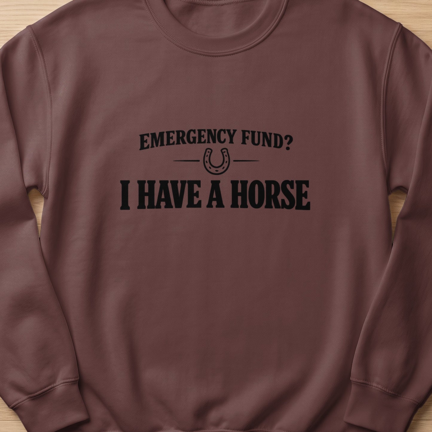 Brown sweatshirt with black text and horseshoe graphic reading "Emergency Fund? I Have A Horse."