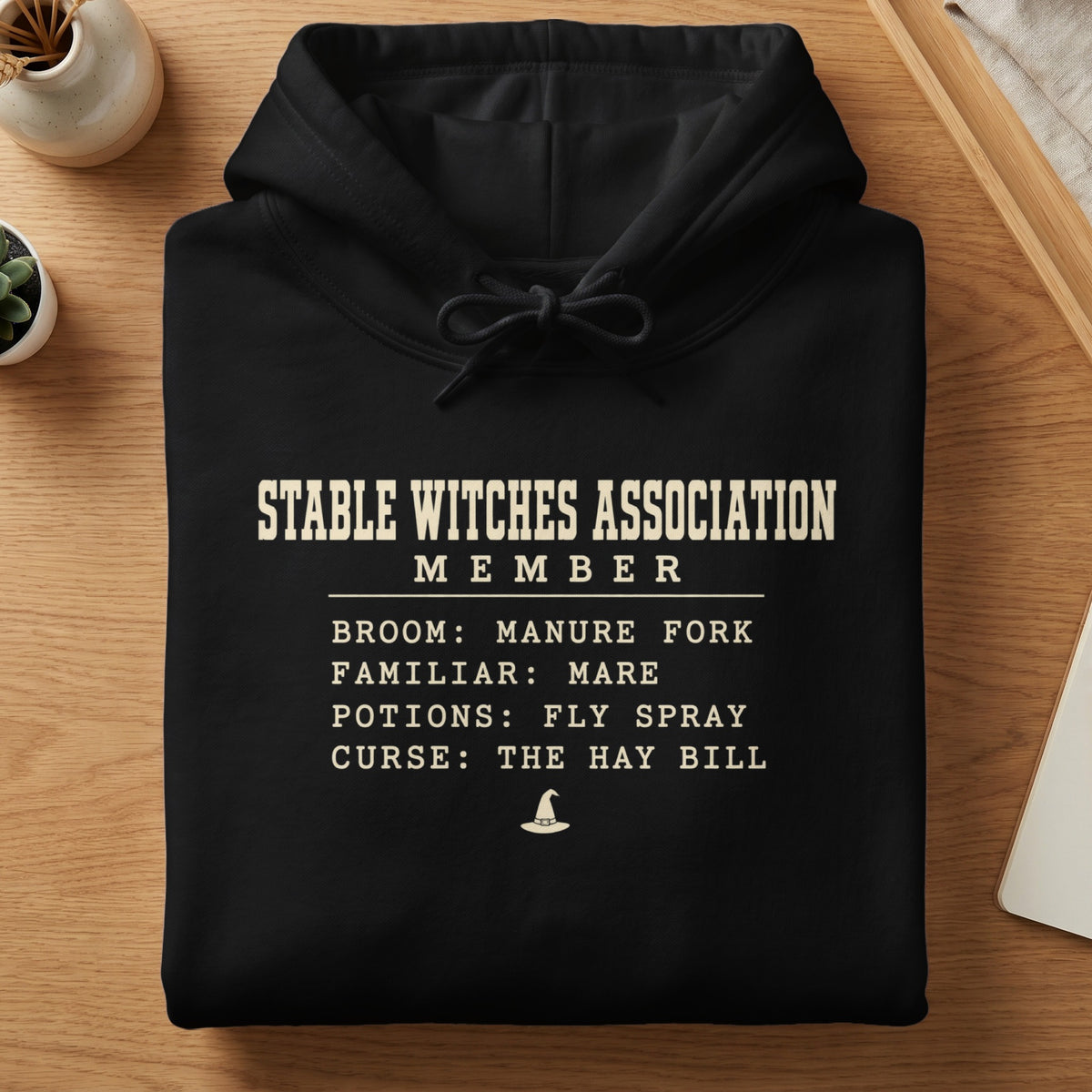 Black hoodie with "Stable Witches Association Member" text and humorous witch-themed list.