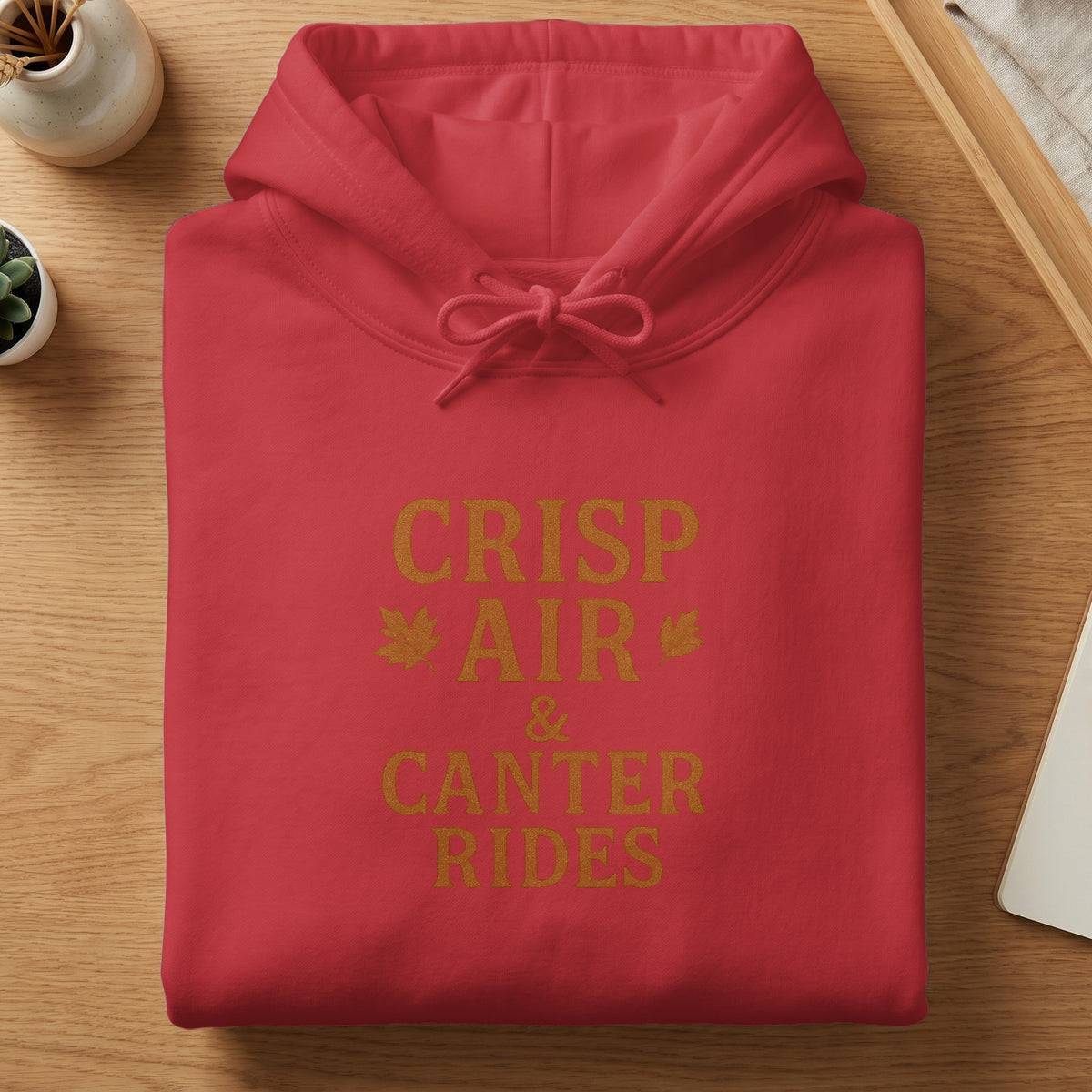 Red hoodie with gold text reading "CRISP AIR & CANTER RIDES" and leaf graphics.