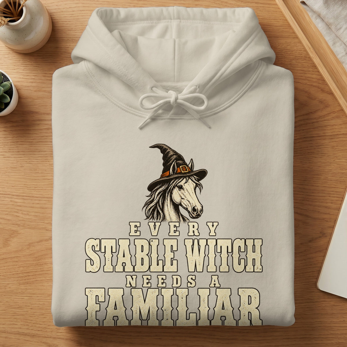 Cream hoodie with a horse wearing a witch hat and text.
