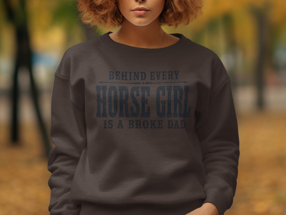 Dark gray sweatshirt with text "BEHIND EVERY HORSE GIRL IS A BROKE DAD".