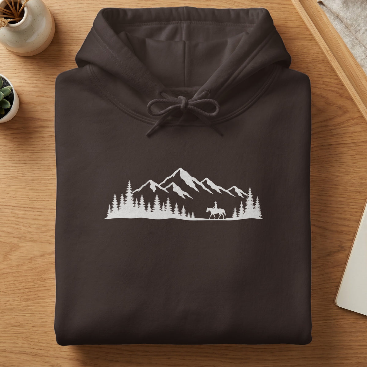 Brown hoodie with white mountain, pine tree, and horseback rider graphic.