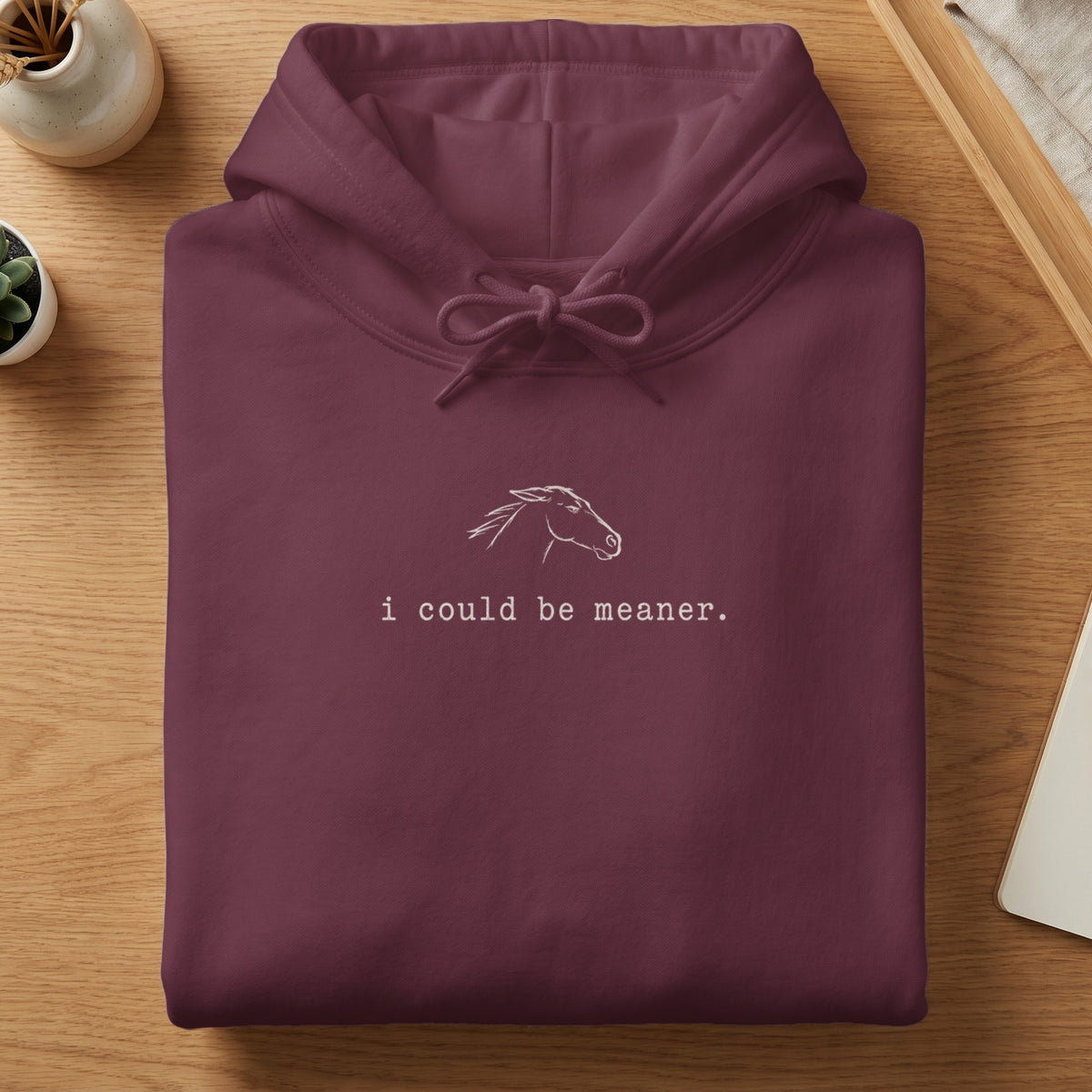 Maroon hoodie with white horse graphic and text "i could be meaner."
