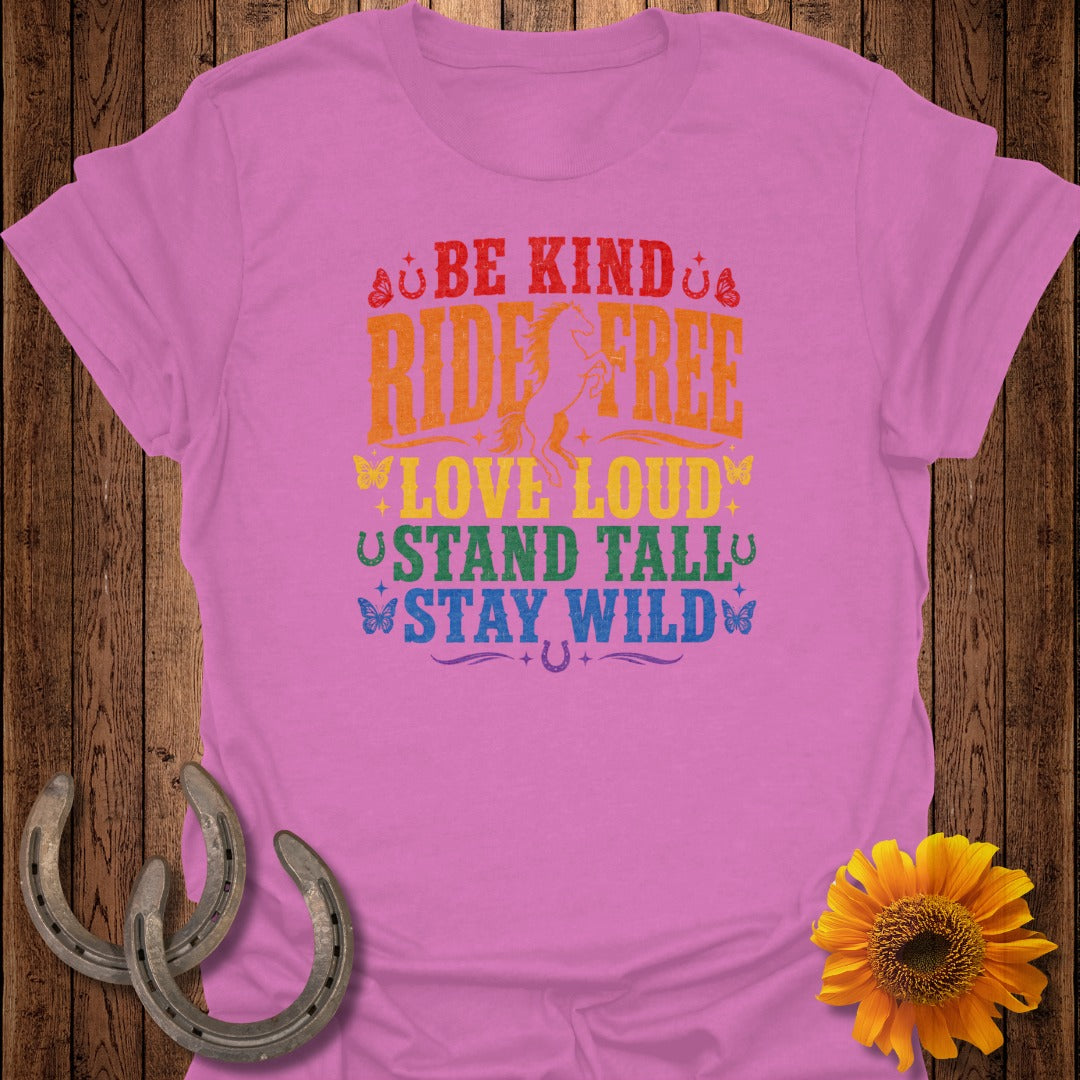 Pink t-shirt with colorful text: "Be Kind Ride Free Love Loud Stand Tall Stay Wild".