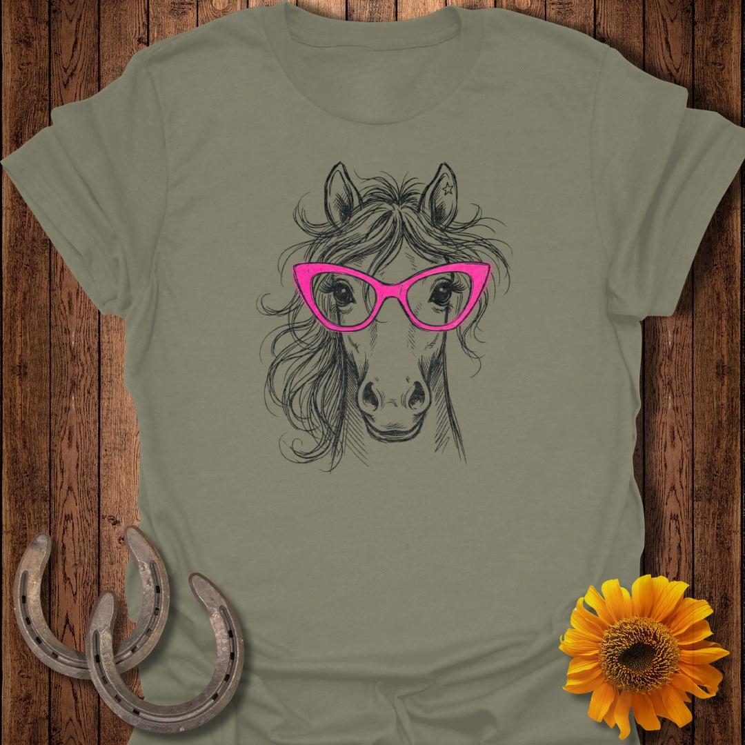 Horse head sketch with pink glasses on a dusty green t-shirt.