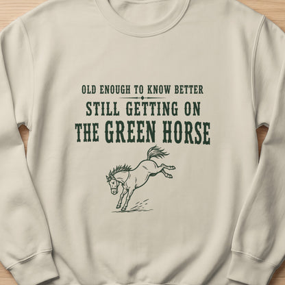 Lightweight crewneck sweatshirt with "Old enough to know better still getting on the green horse" text and horse graphic.