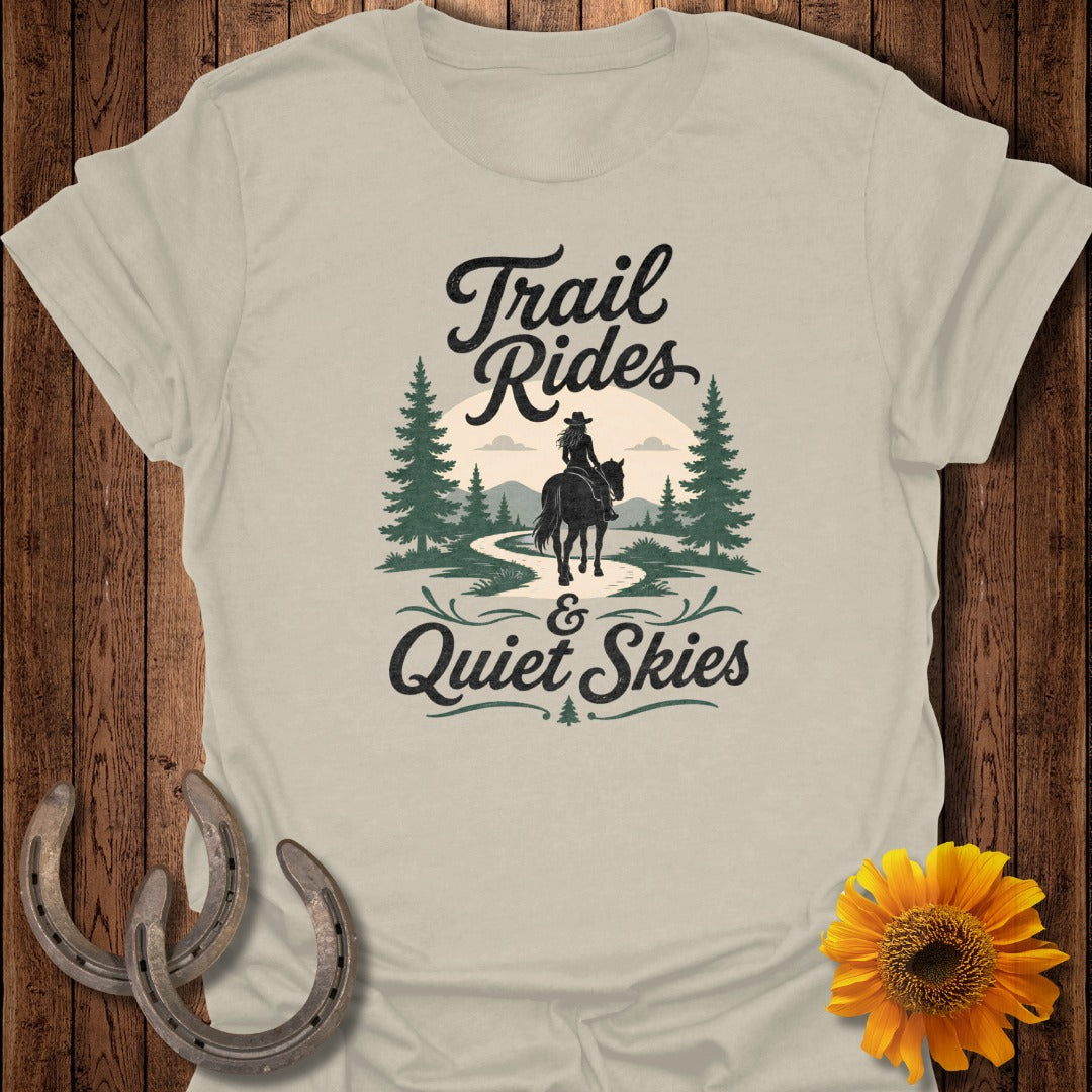 "Trail Rides & Quiet Skies" text on a light tan t-shirt with a cowboy on horseback.