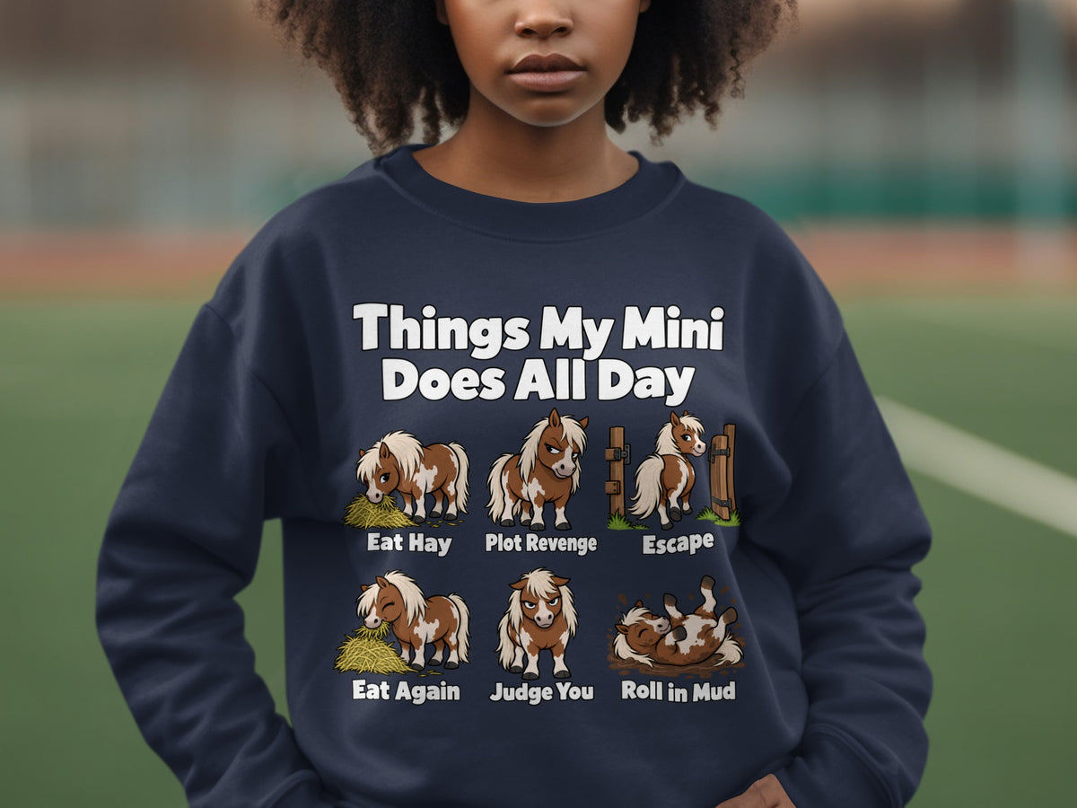 A person wears a dark blue sweatshirt with cartoon mini horses and text listing daily activities.