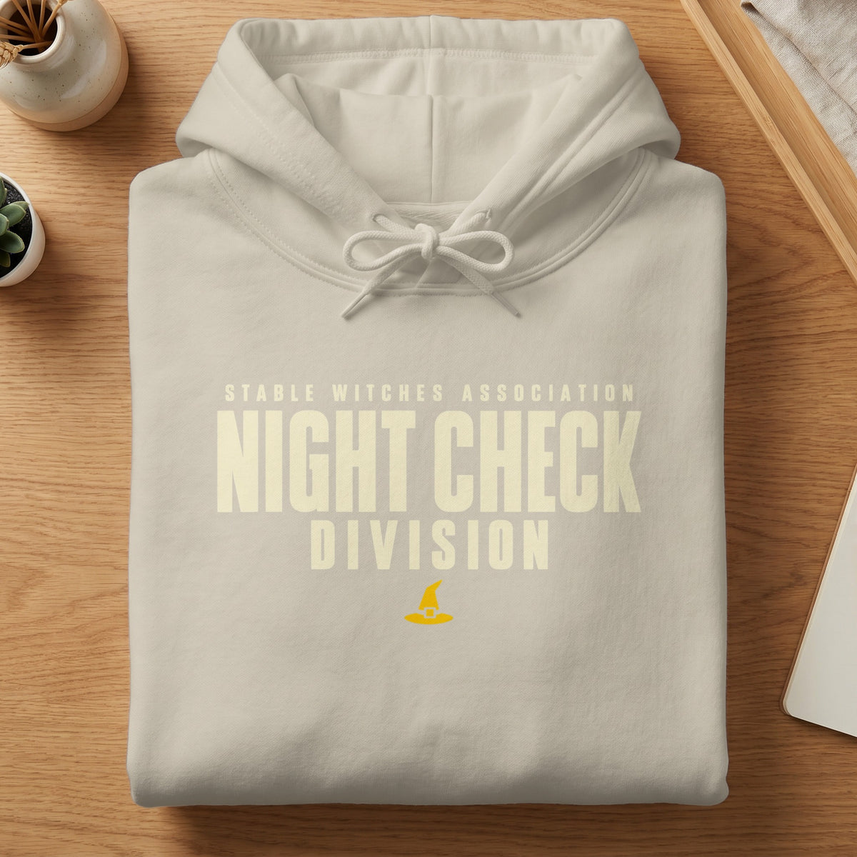 Cream hoodie with "Stable Witches Association Night Check Division" text and witch hat.