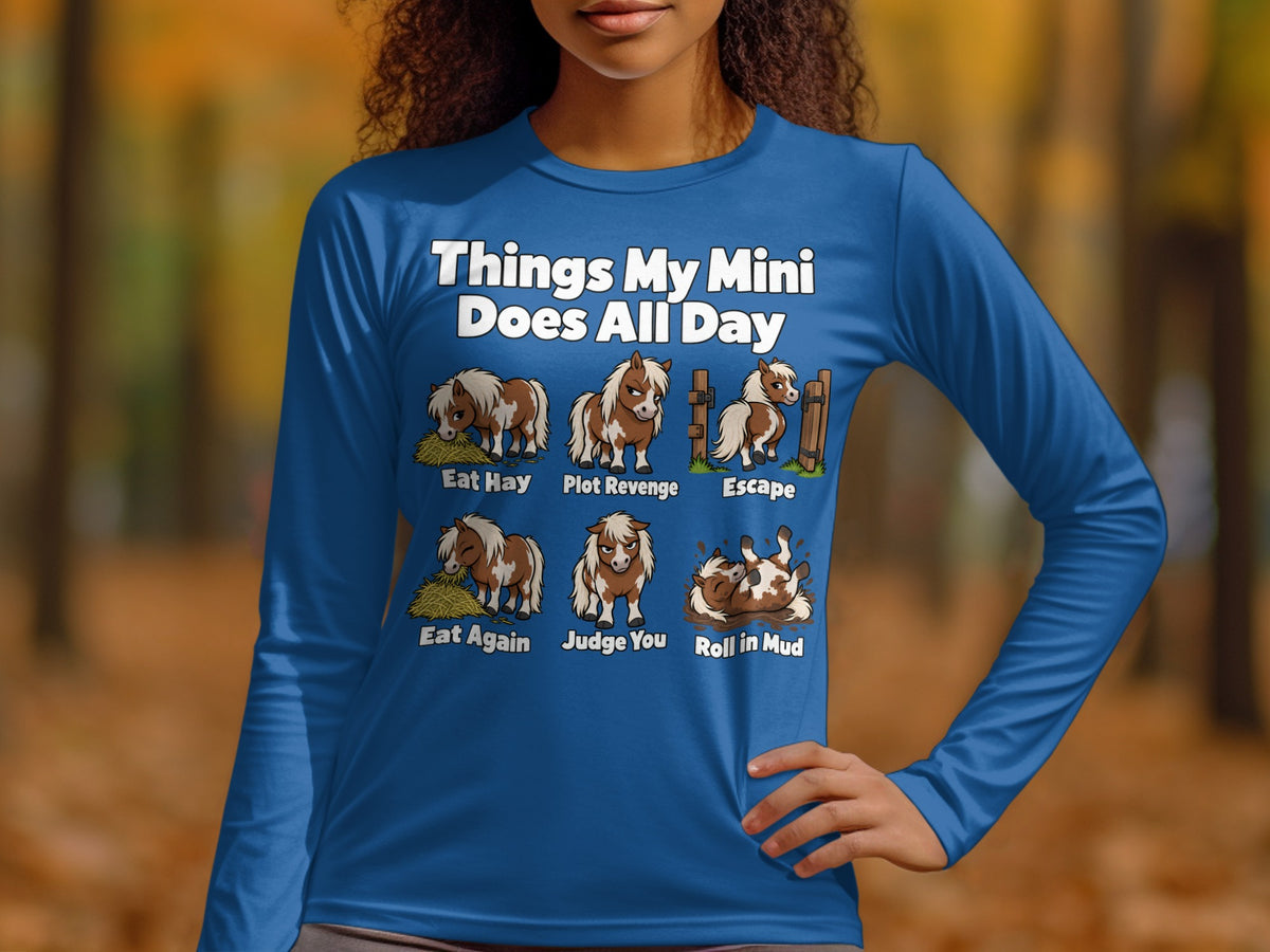 A person wearing a royal blue long-sleeve shirt with humorous illustrations and text about miniature horses.