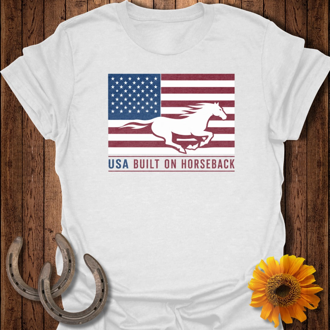 White t-shirt with American flag, running horse, and "USA BUILT ON HORSEBACK" text.
