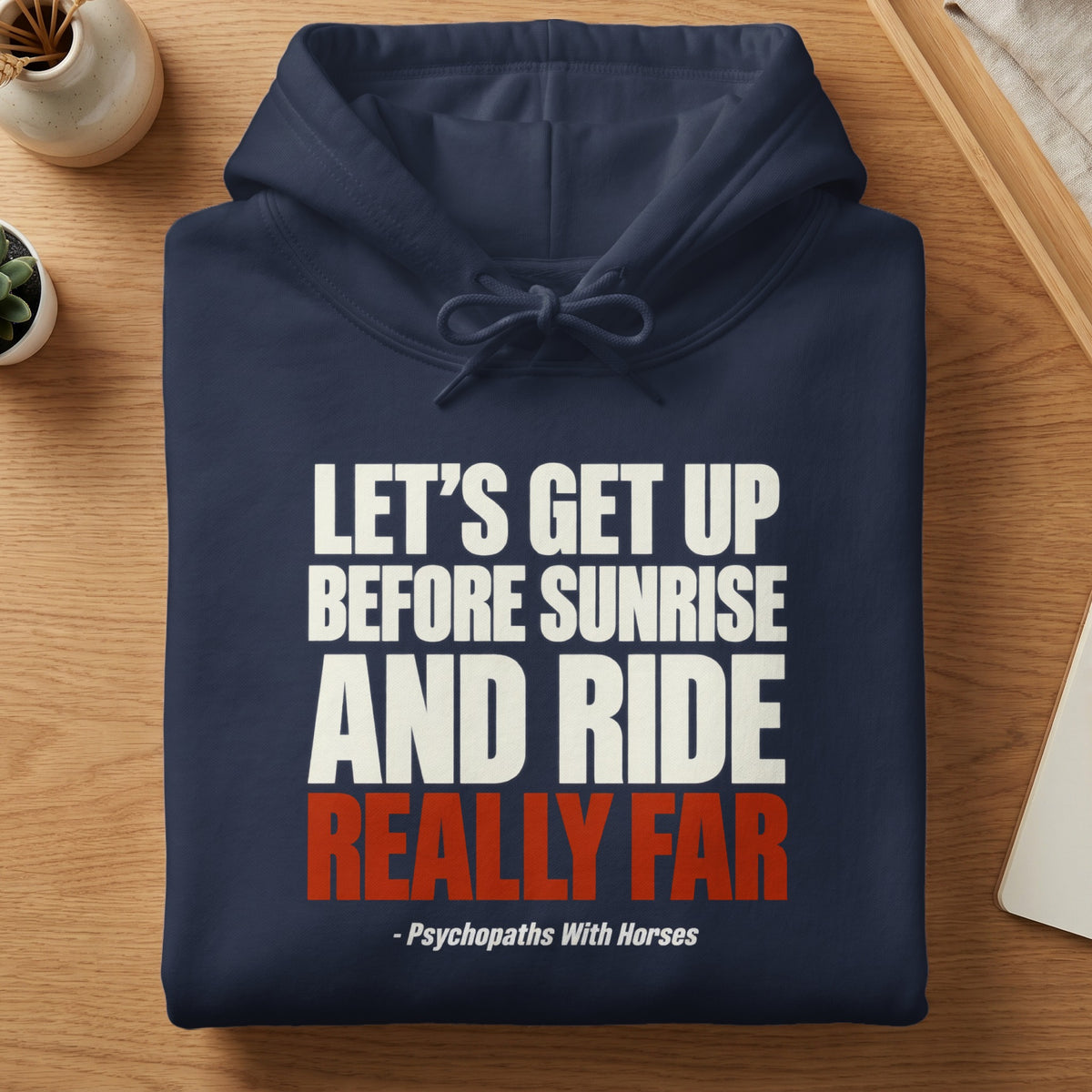 A folded dark blue hoodie featuring white and red text that reads Let’s Get Up Before Sunrise And Ride Really Far - Psychopaths With Horses.