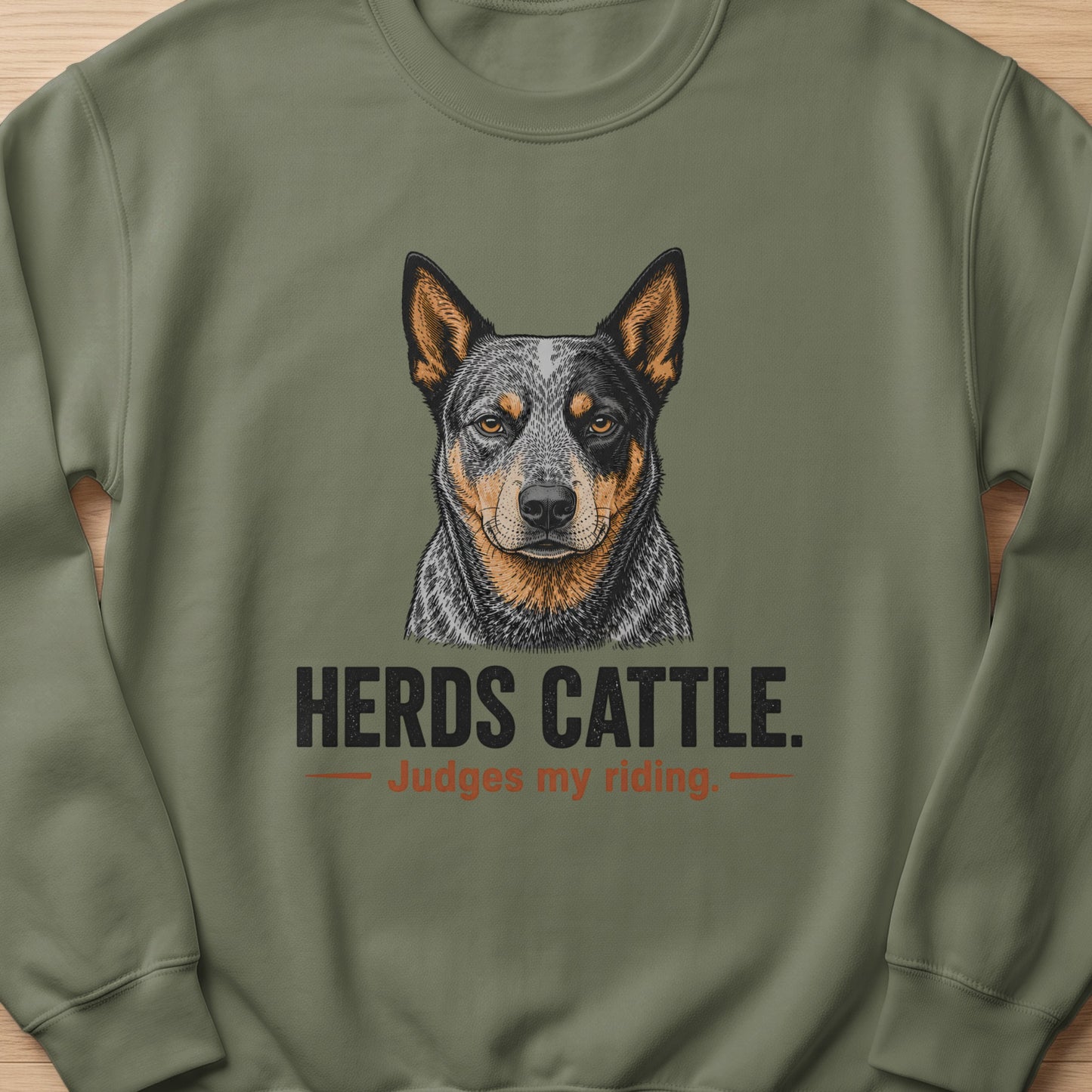 Crewneck sweatshirt with a drawing of an Australian Cattle Dog and text "HERDS CATTLE. Judges my riding."