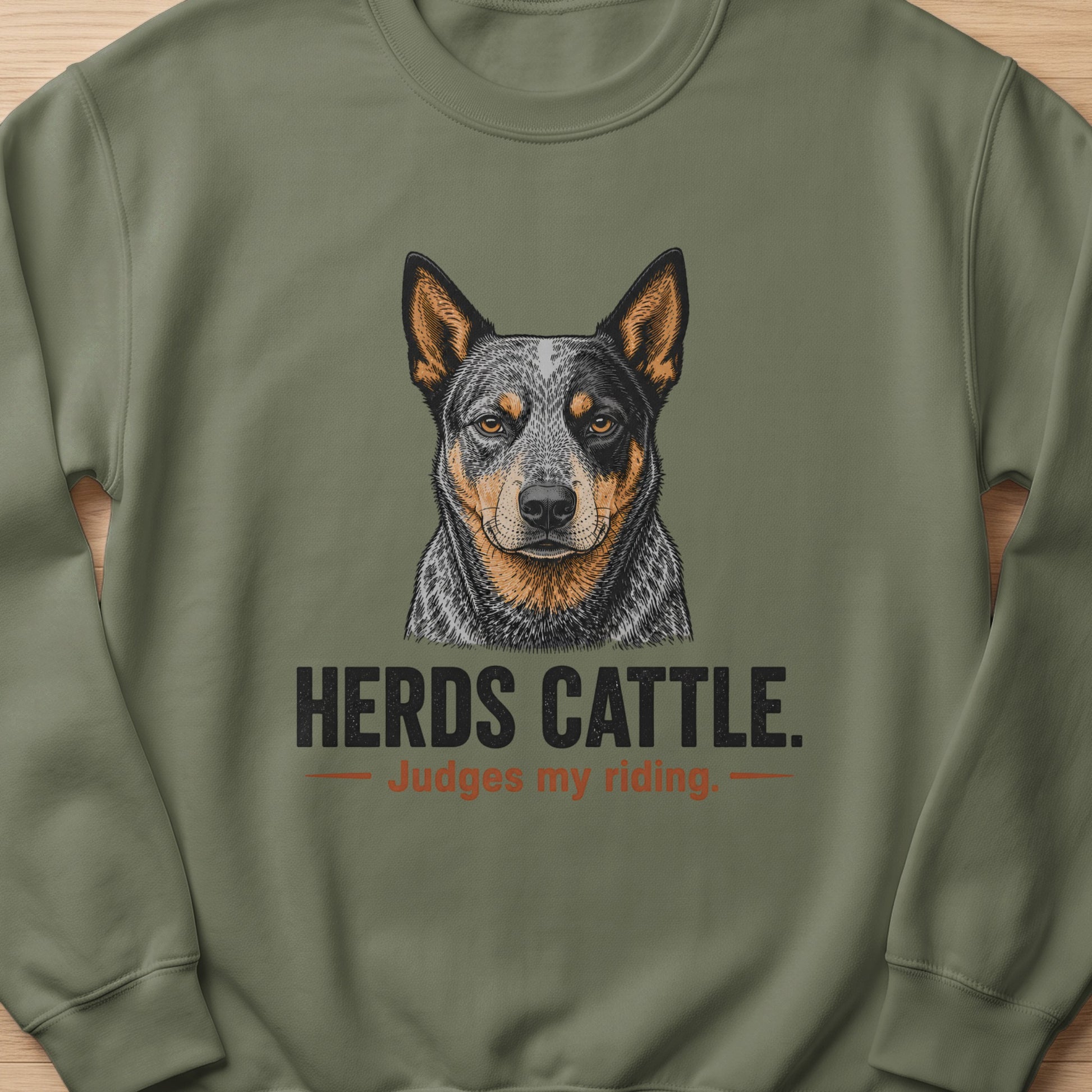 Crewneck sweatshirt with a drawing of an Australian Cattle Dog and text "HERDS CATTLE. Judges my riding."