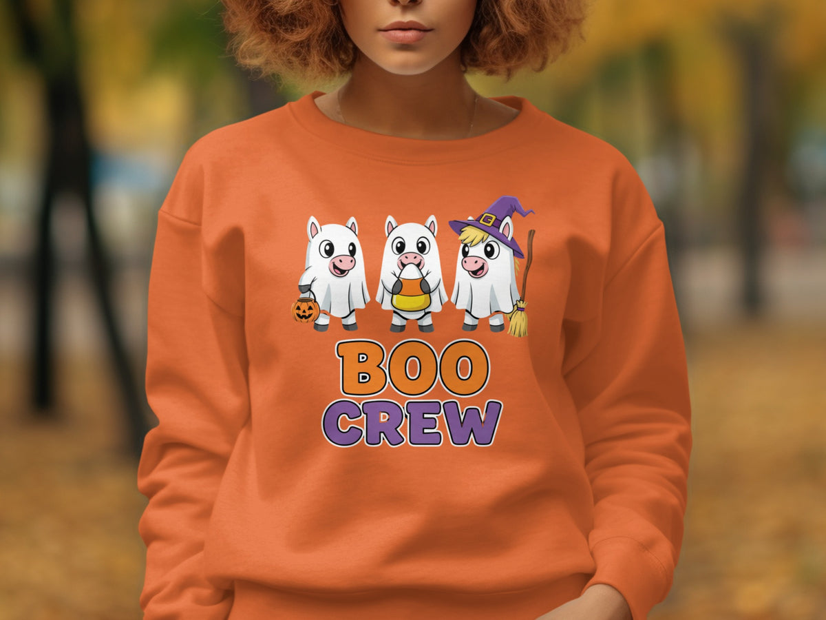 Orange sweatshirt with "Boo Crew" text and three ghost unicorns with Halloween props.