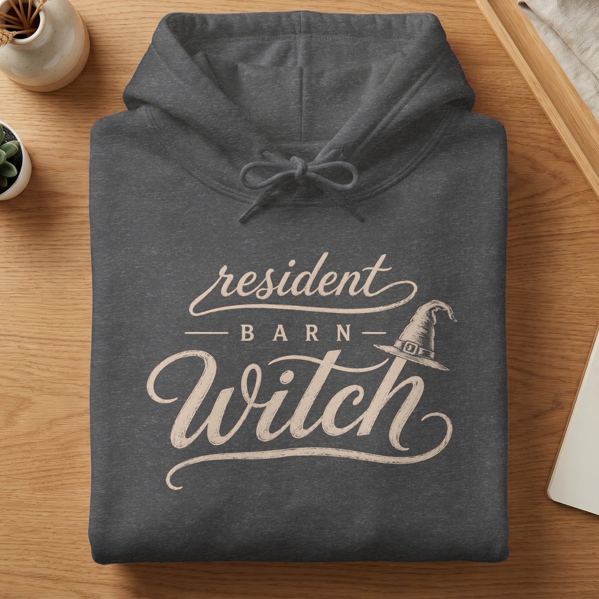 Dark grey hoodie with cream text reading "resident barn witch" and a witch hat graphic.