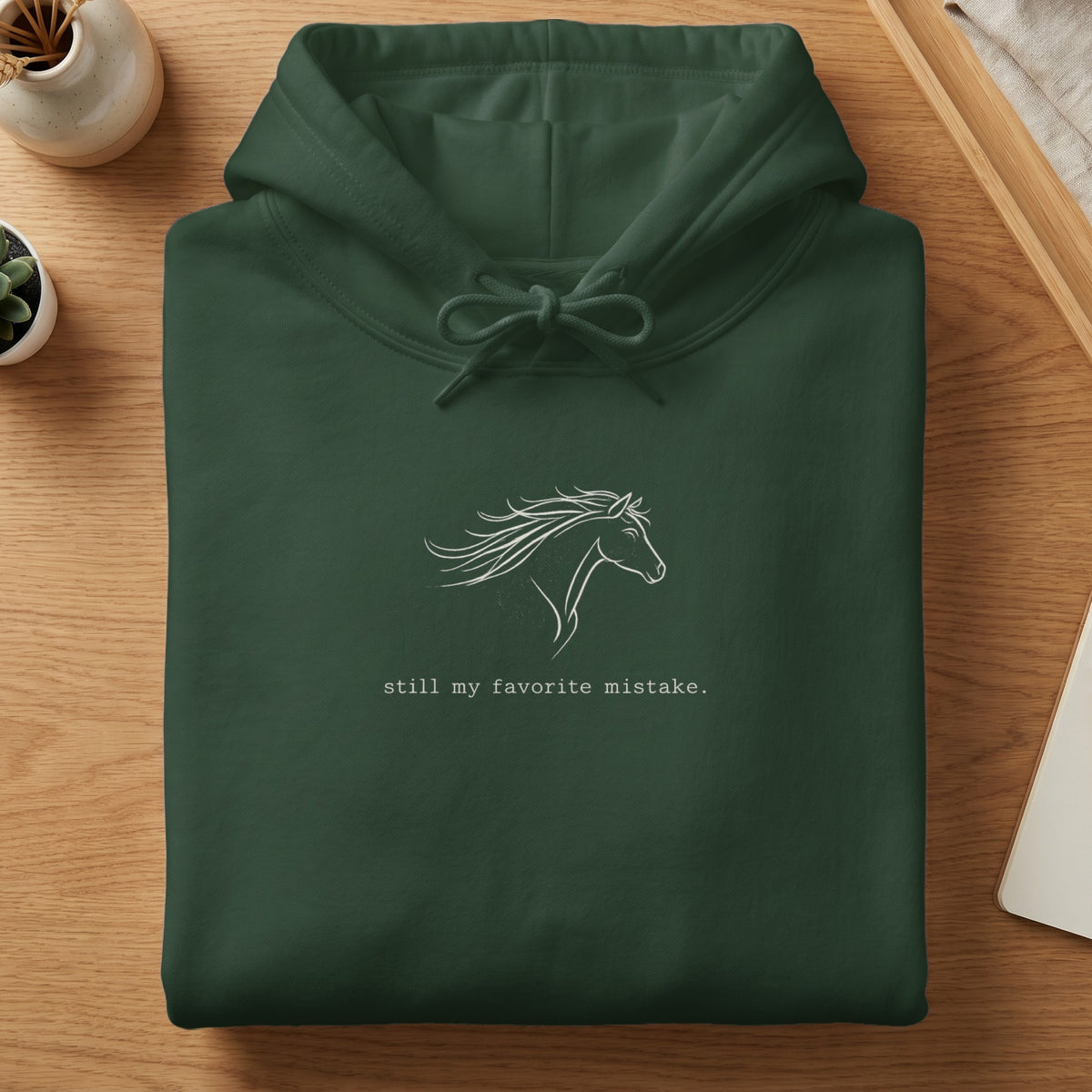 Dark green hoodie with white horse graphic and text "still my favorite mistake."