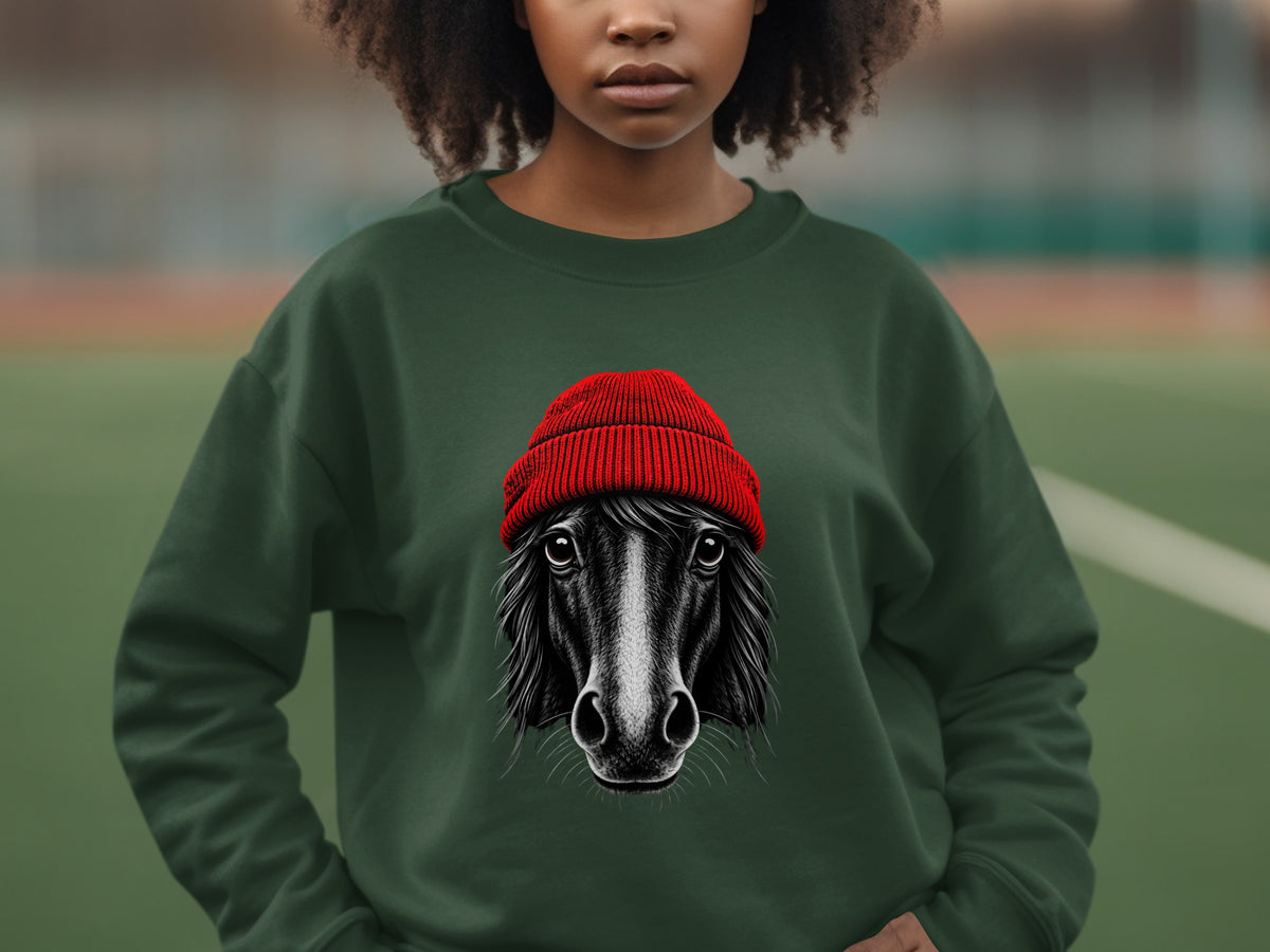 A person wearing a dark green crewneck sweatshirt featuring an illustration of a black horse wearing a red knit beanie.