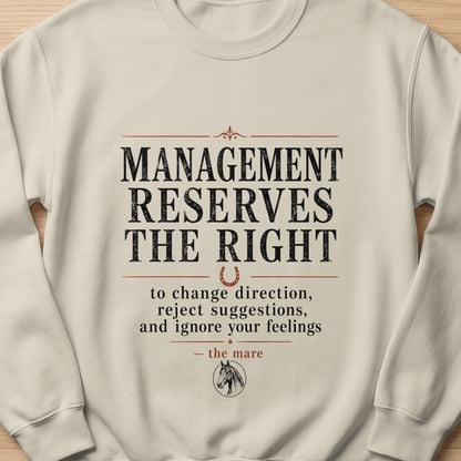 Cream sweatshirt with text "Management reserves the right to change direction, reject suggestions, and ignore your feelings - the mare".