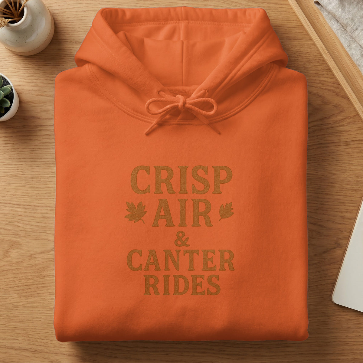 Orange hoodie with "CRISP AIR & CANTER RIDES" text and leaf accents.