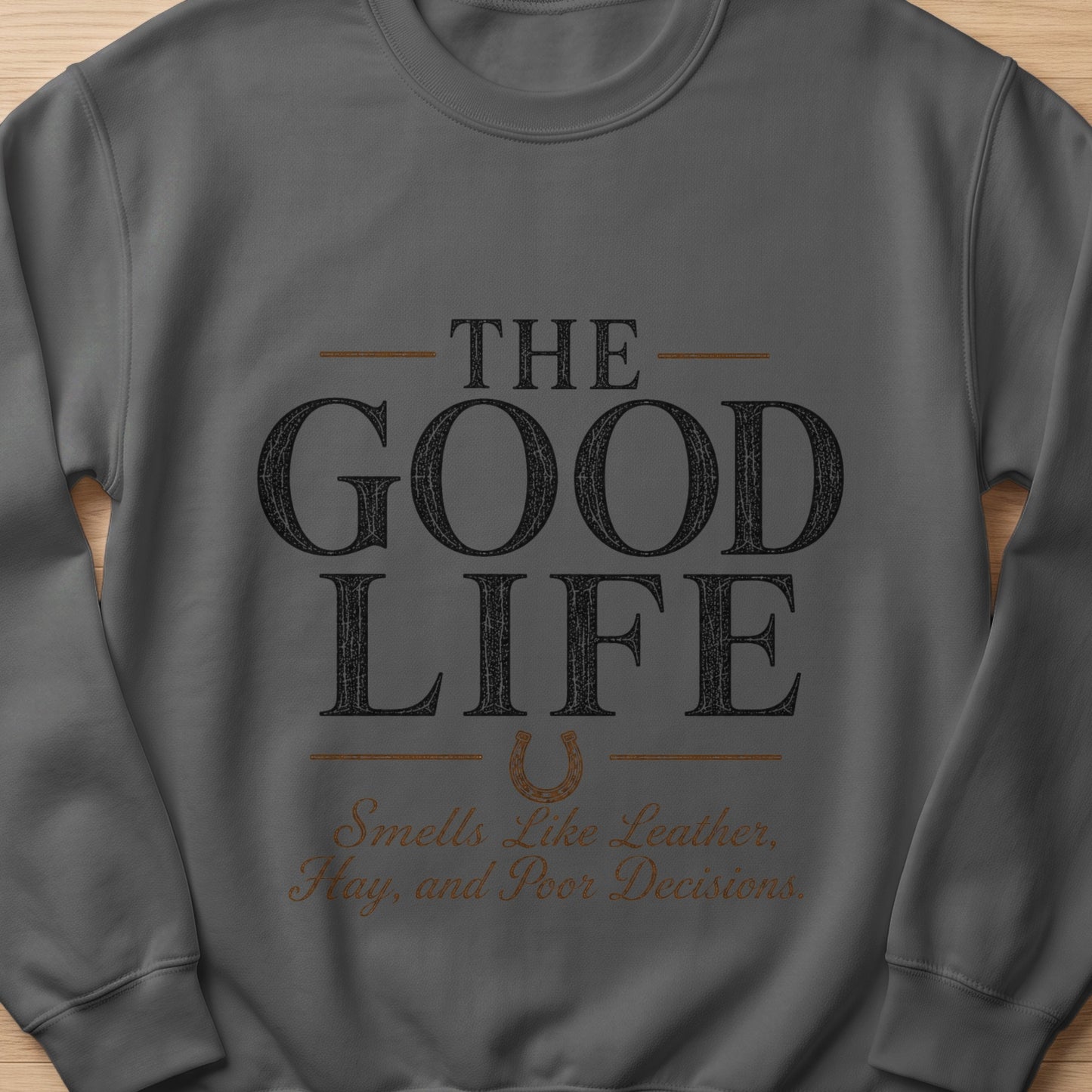 Grey sweatshirt with text "The Good Life" and "Smells Like Leather, Hay, and Poor Decisions".