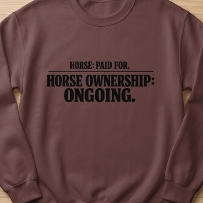 Brown sweatshirt with black text reading "HORSE: PAID FOR. HORSE OWNERSHIP: ONGOING."