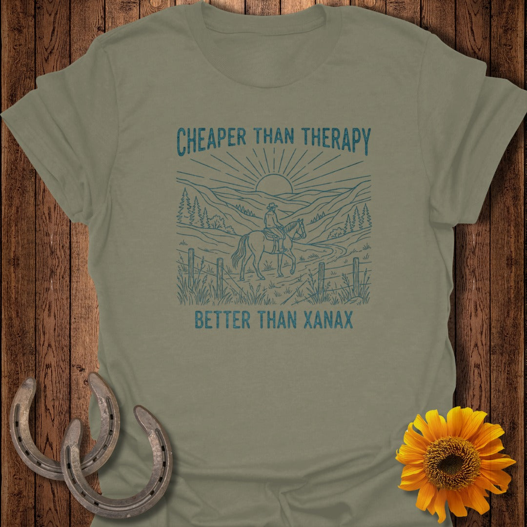 Sage green t-shirt with a graphic of a rider on a horse in a mountainous landscape.